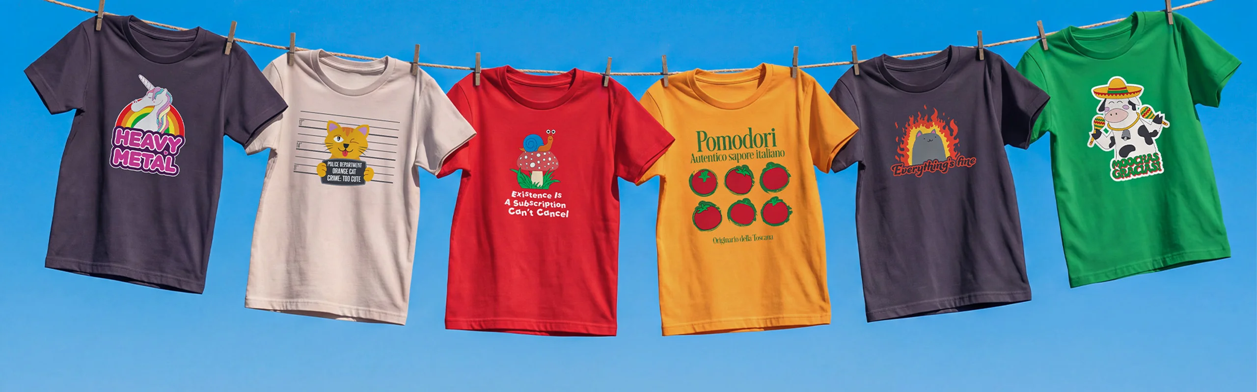 Six graphic T-shirts pegged to a clothesline against a clear blue sky